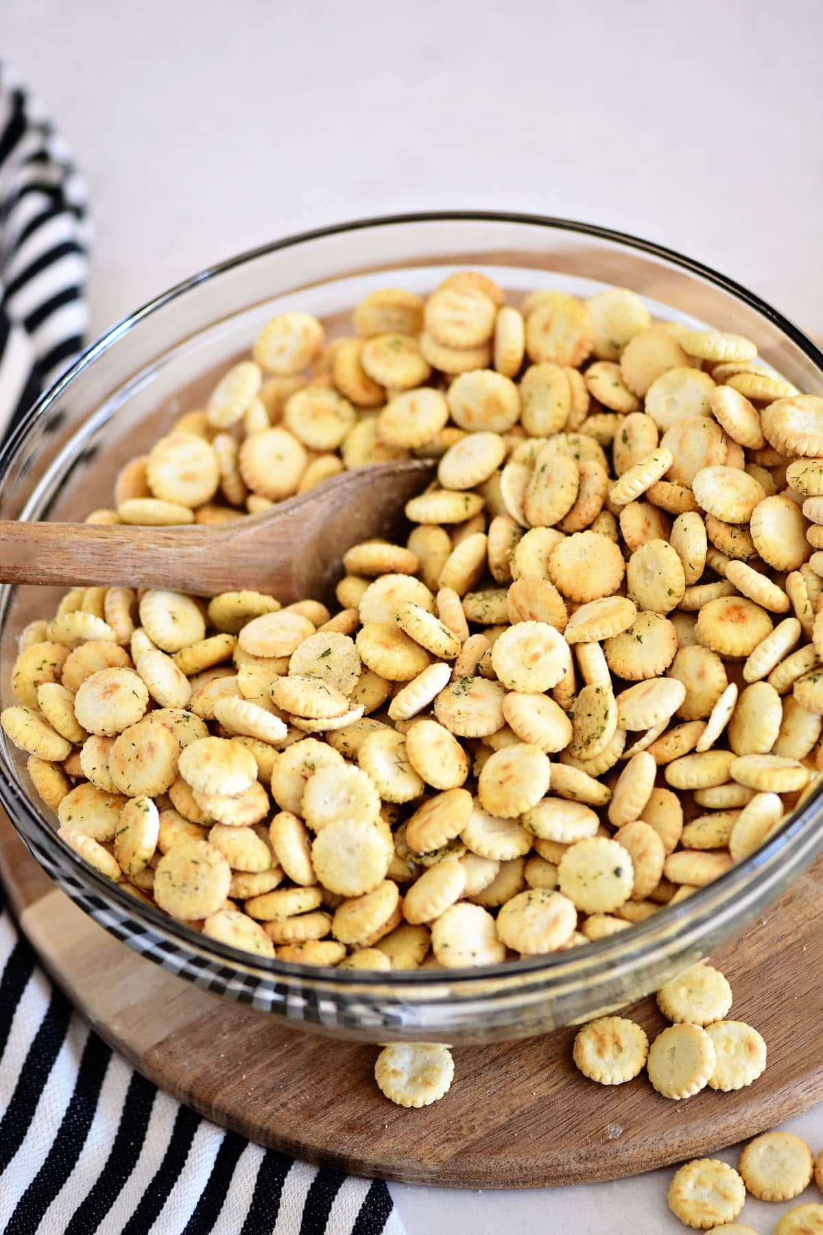 adding ranch dressing mix and seasonings to oyster crackers in a glass bowl