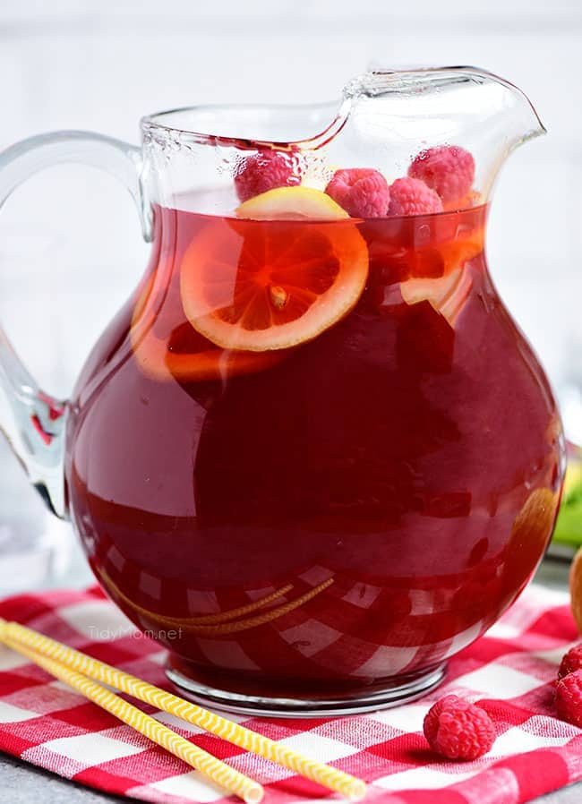 A pitcher of Red Raspberry Iced Tea with lemon slices and raspberries