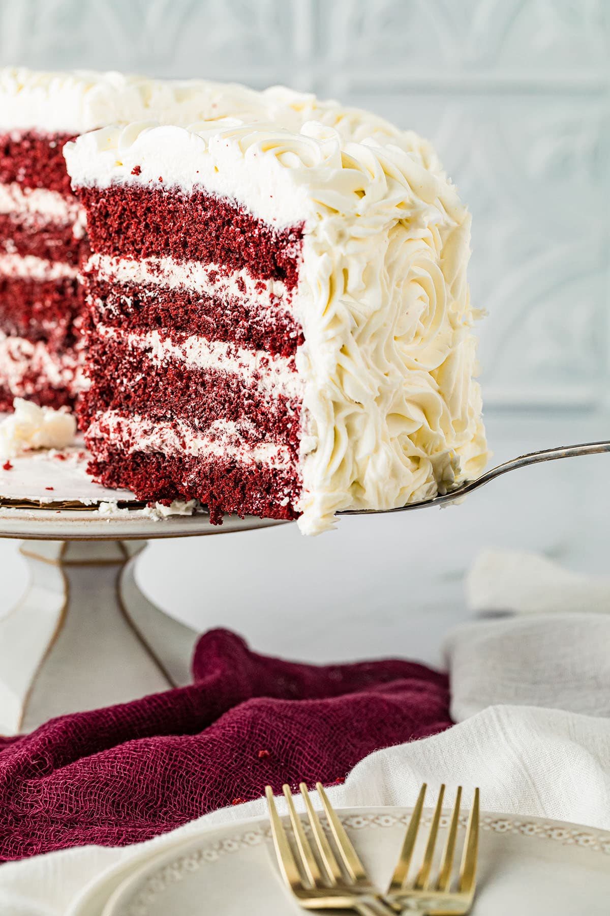 Serving a slice of red velvet cake with cinnamon buttercream on a cake stand.