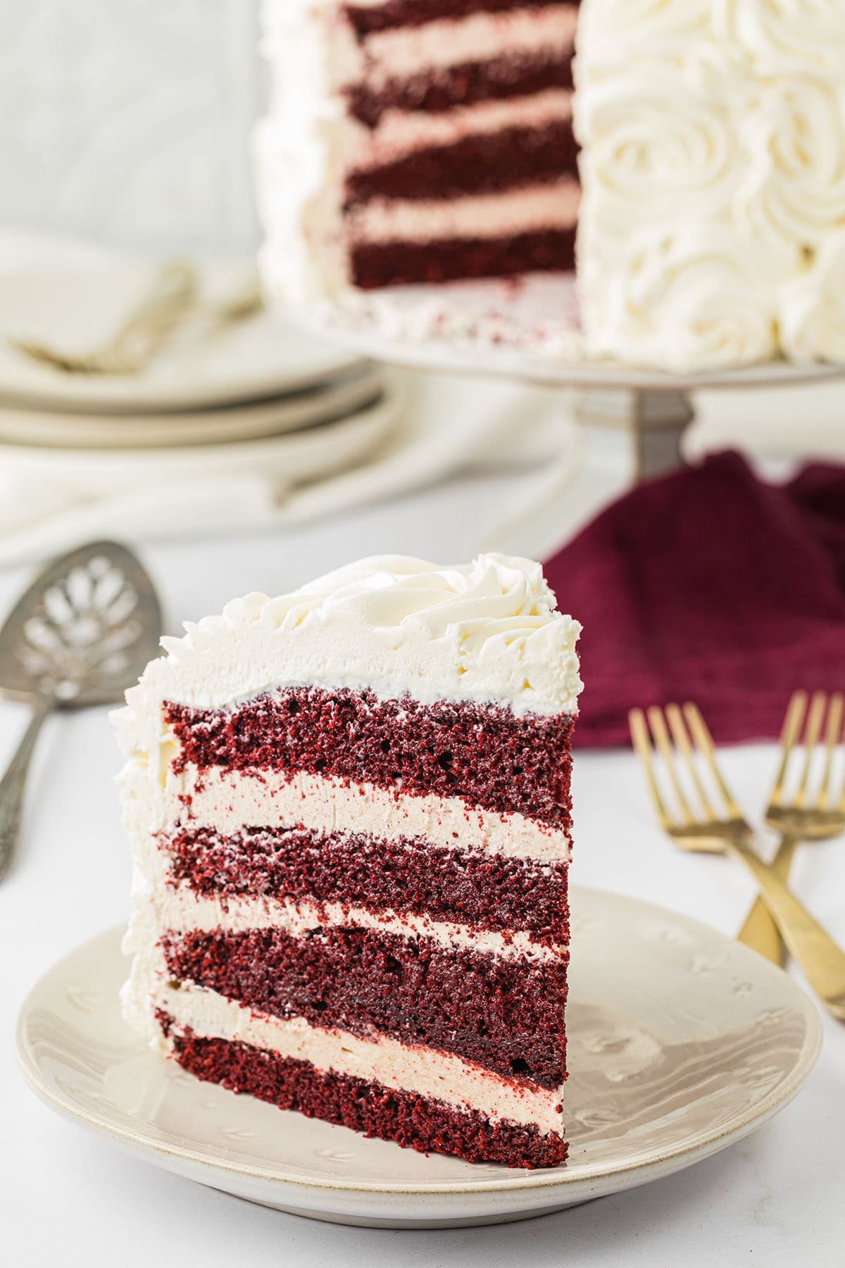 Serving a slice of red velvet cake with cinnamon buttercream on a plate.