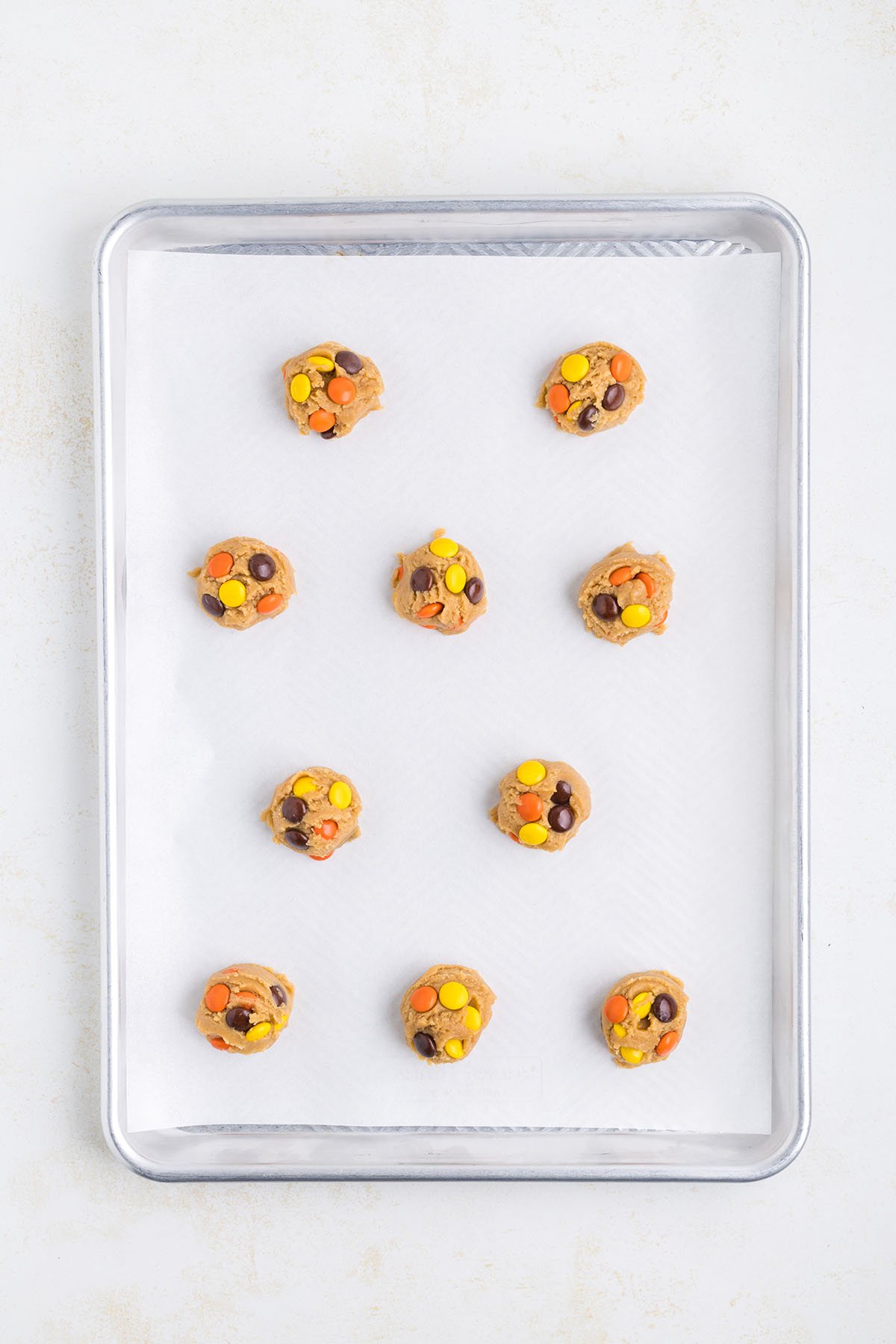Cookie dough balls on a baking sheet with parchment paper