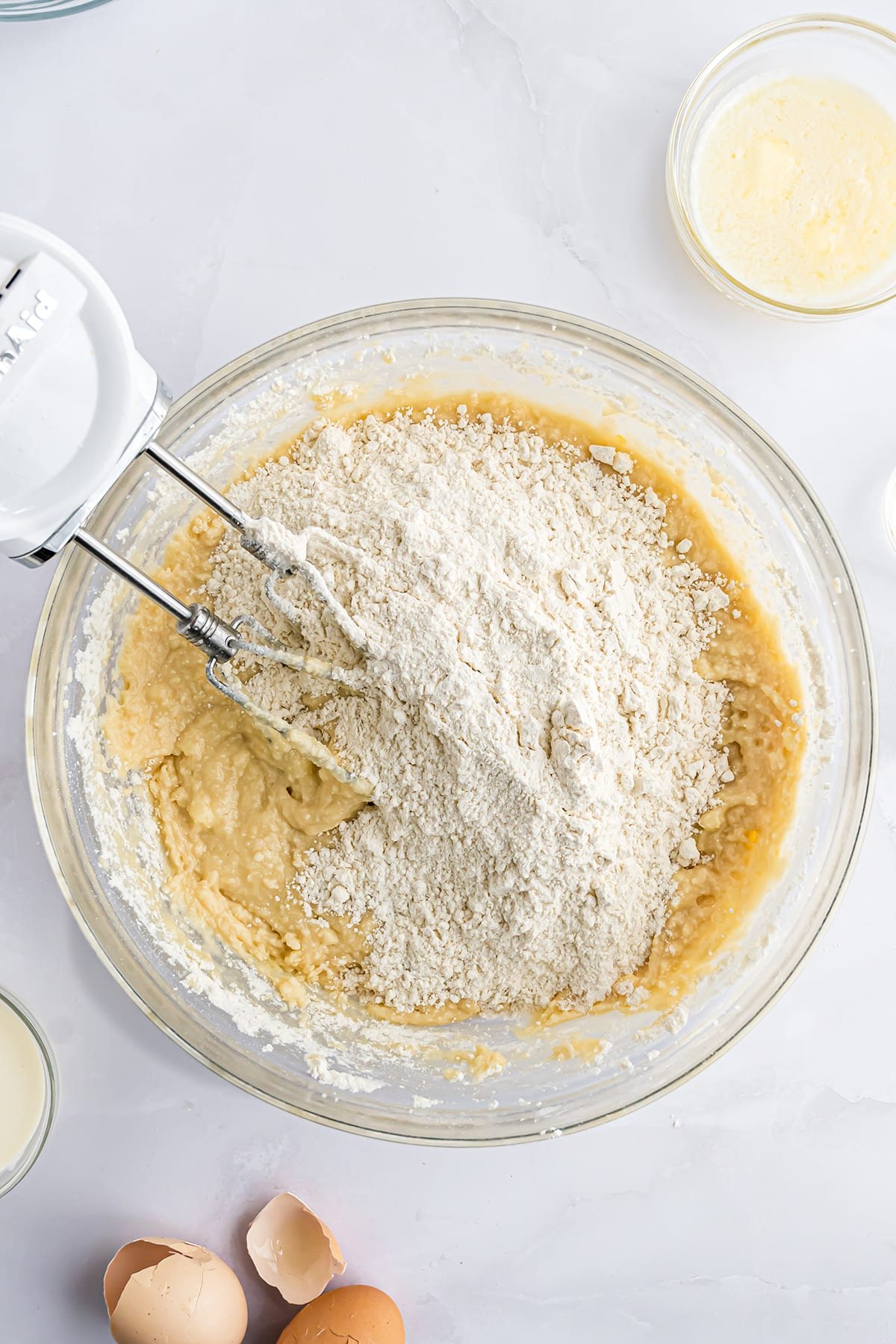 mixing cookie dough in a glass bowl with an electric hand mixer
