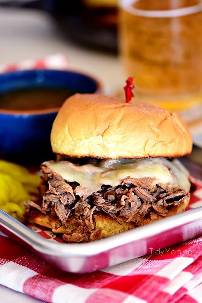 Italian beef sandwich with cheese and a bowl of au jus