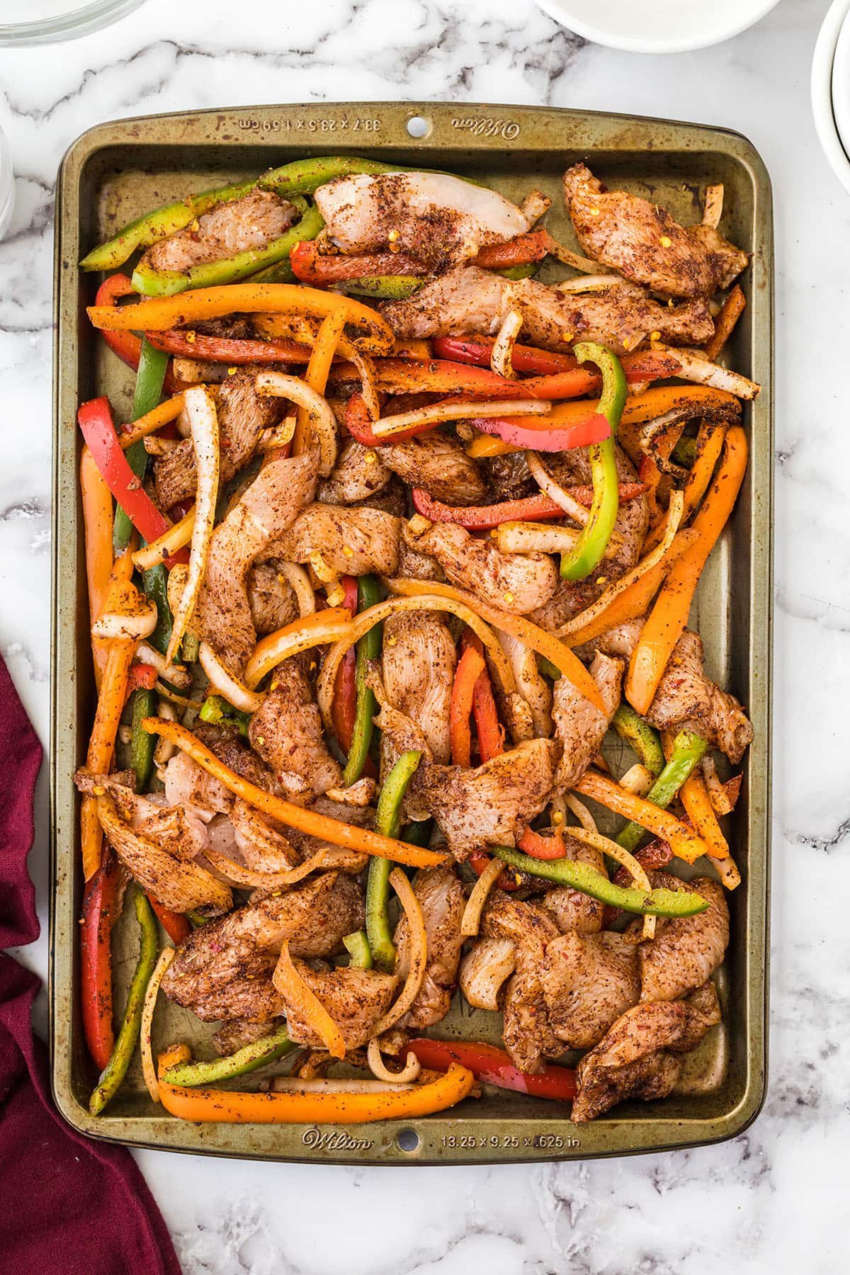 chicken and veggies ion a sheet pan with fajita seasonings