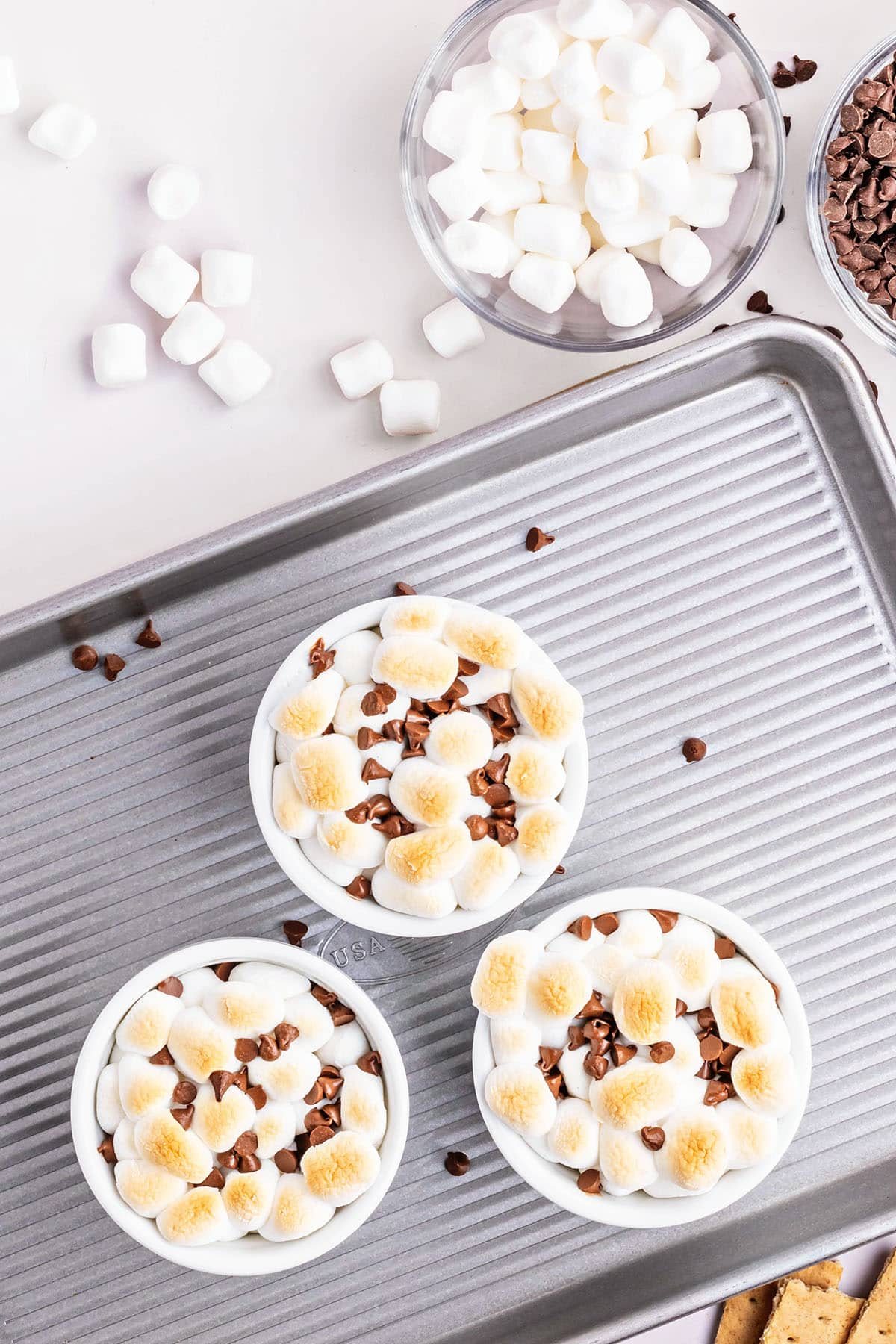 3 ramekins with oven baked s'mores dip on a baking sheet