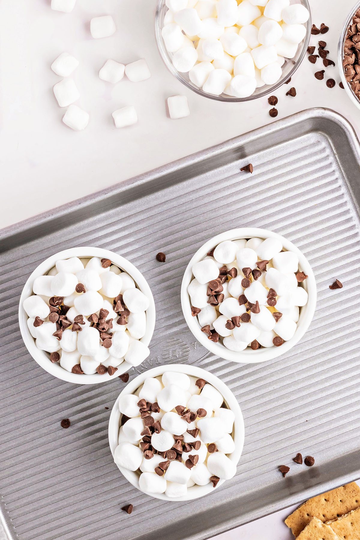 3 ramekins with s'mores dip ready for the oven on a baking sheet