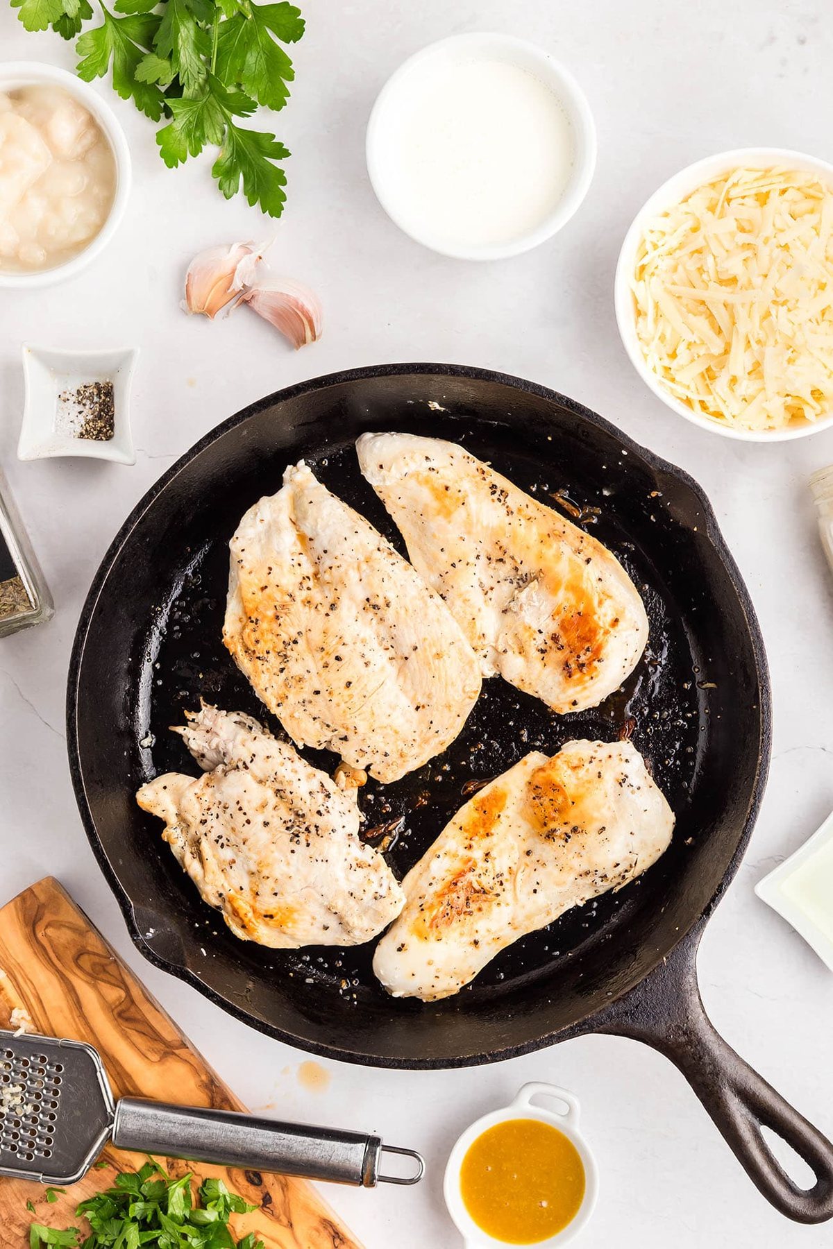 Chicken breasts searing in a skillet for one-skillet smothered chicken.