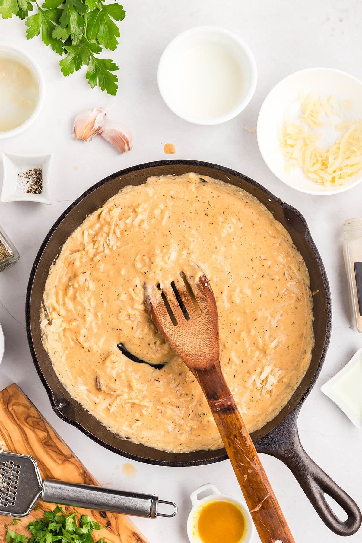 Parmesan cheese being added to the creamy sauce in the skillet.