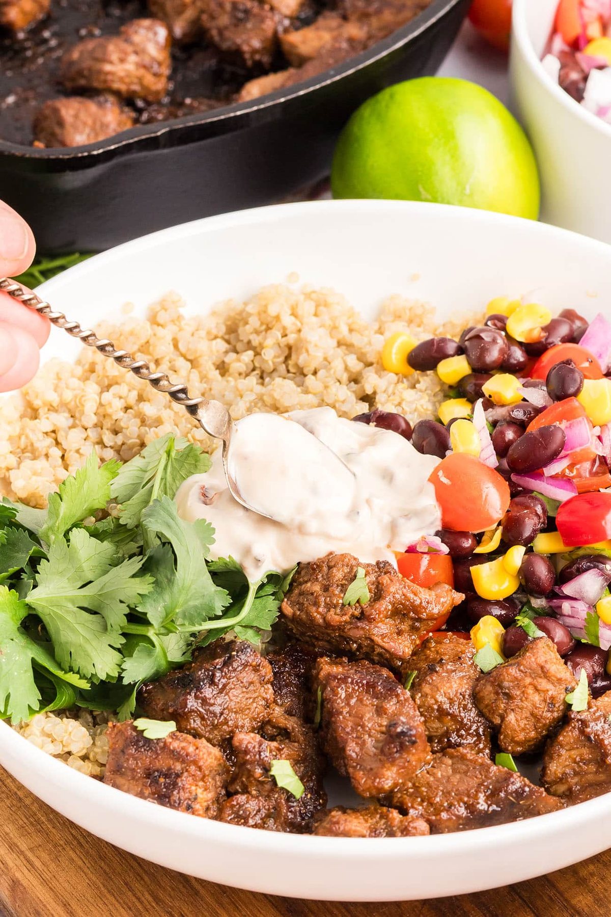 Close-up of a Southwest steak bowl with tender sirloin steak, rice, black bean and corn salad, and creamy Southwest sauce.