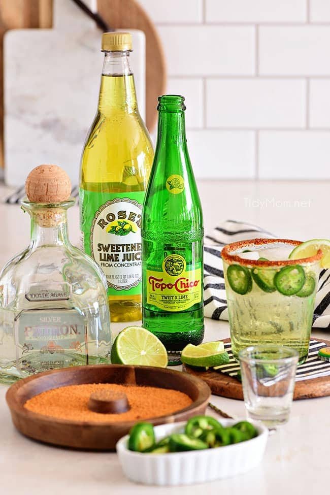 ranch water ingredients - a bottle of tequila, Topo Chico and lime juice on a counter