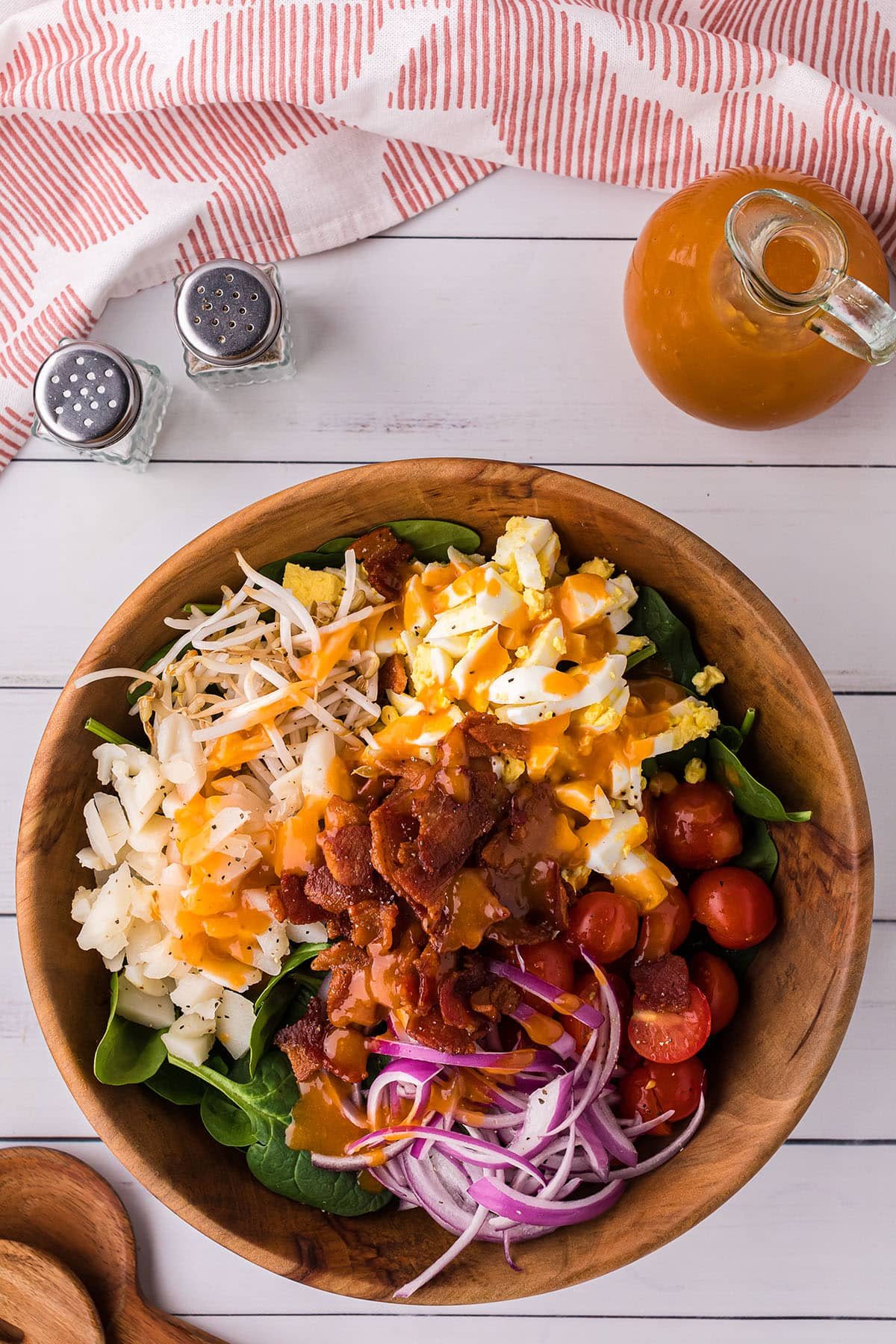 spinach salad with a bottle of homemade dressing next to the salad