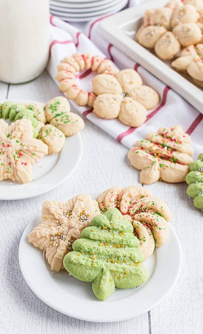 Holiday spritz cookies on a plate with a glass of milk