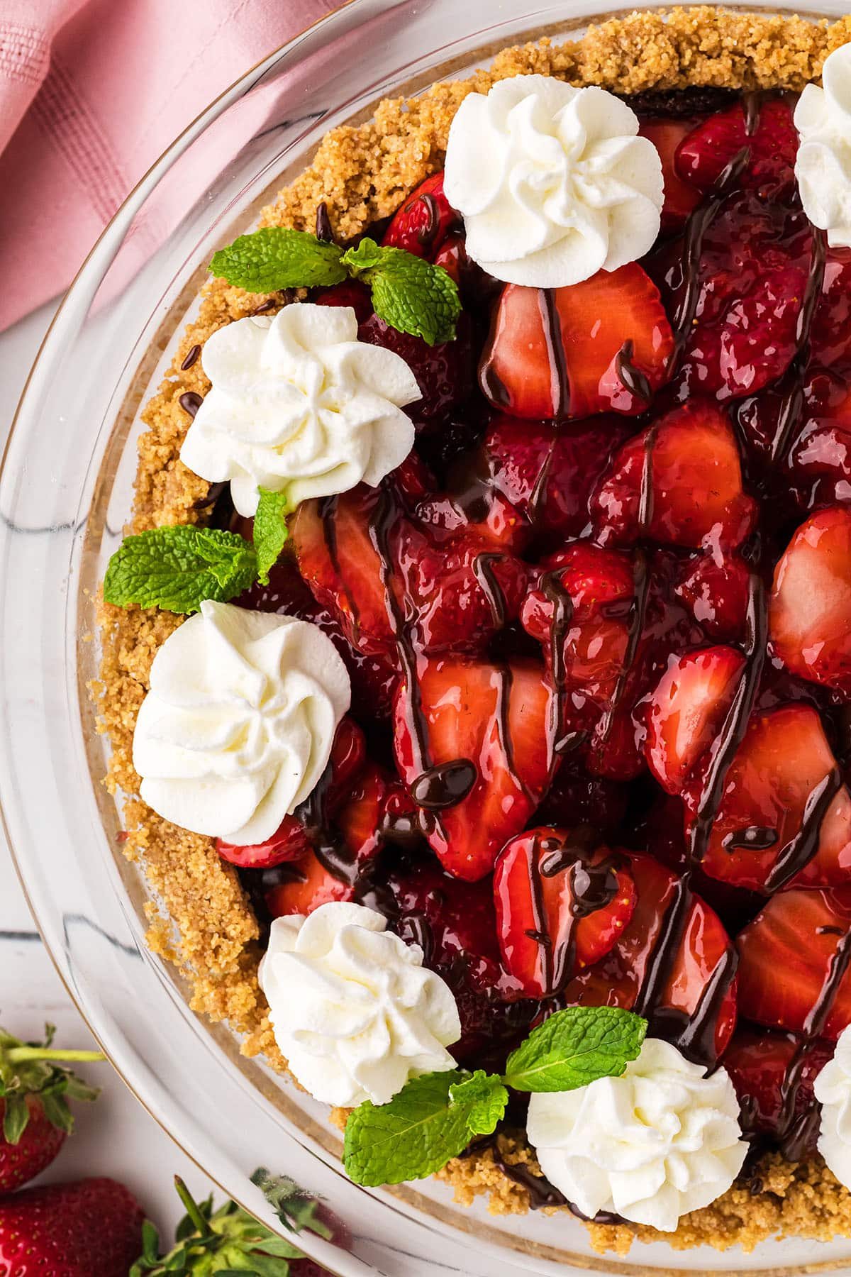 overhead shot of half a pie with fresh strawberries, whipped cream and mint leaves