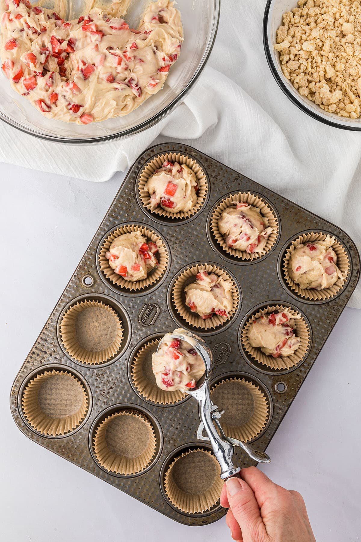 scooping muffin batter into a pan