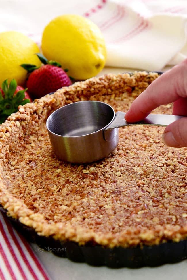 pressing out a pretzel pie crust with a measuring cup