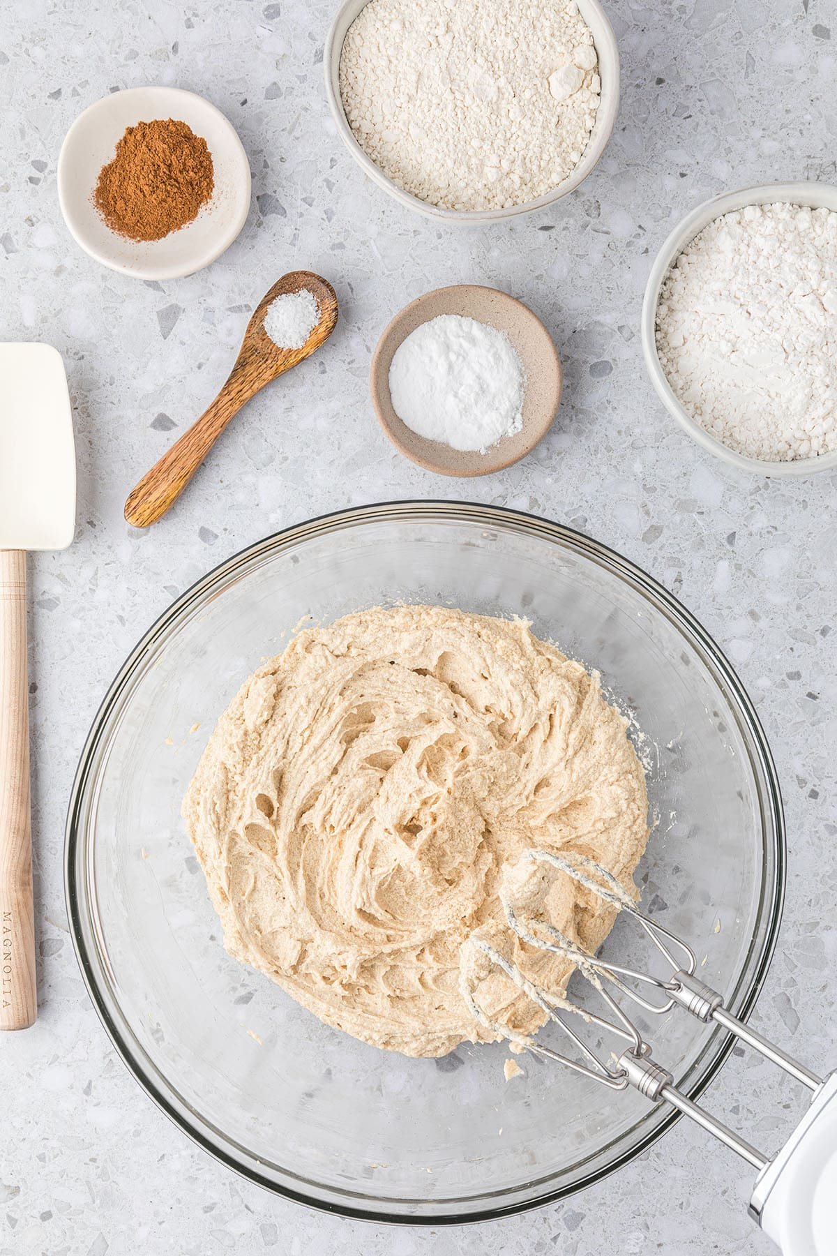 glass mixing bowl with cookie dough and electric hand mixer