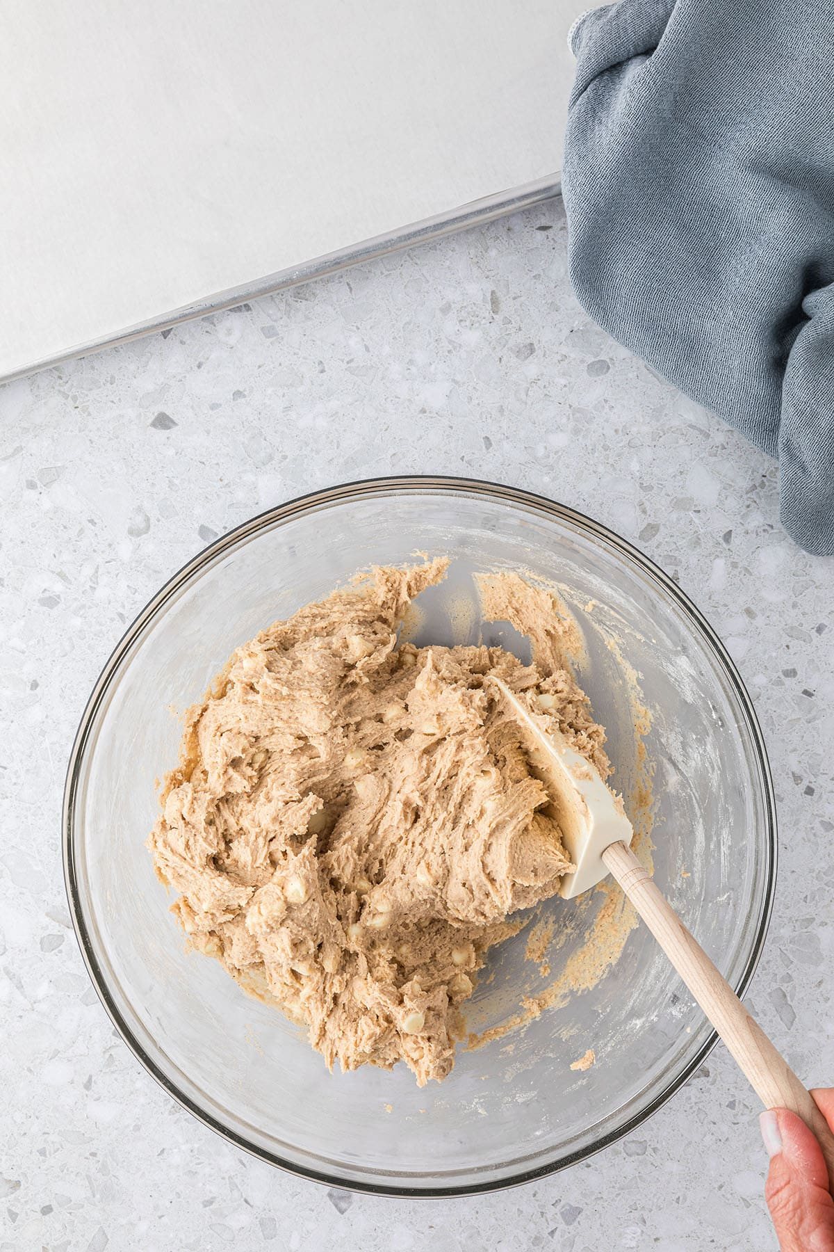 glass mixing bowl with cinnamon sugar cookie dough and spatula folding in white chocolate chips
