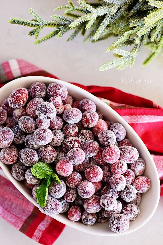 sugared cranberries in an oval bowl with Christmas napkin