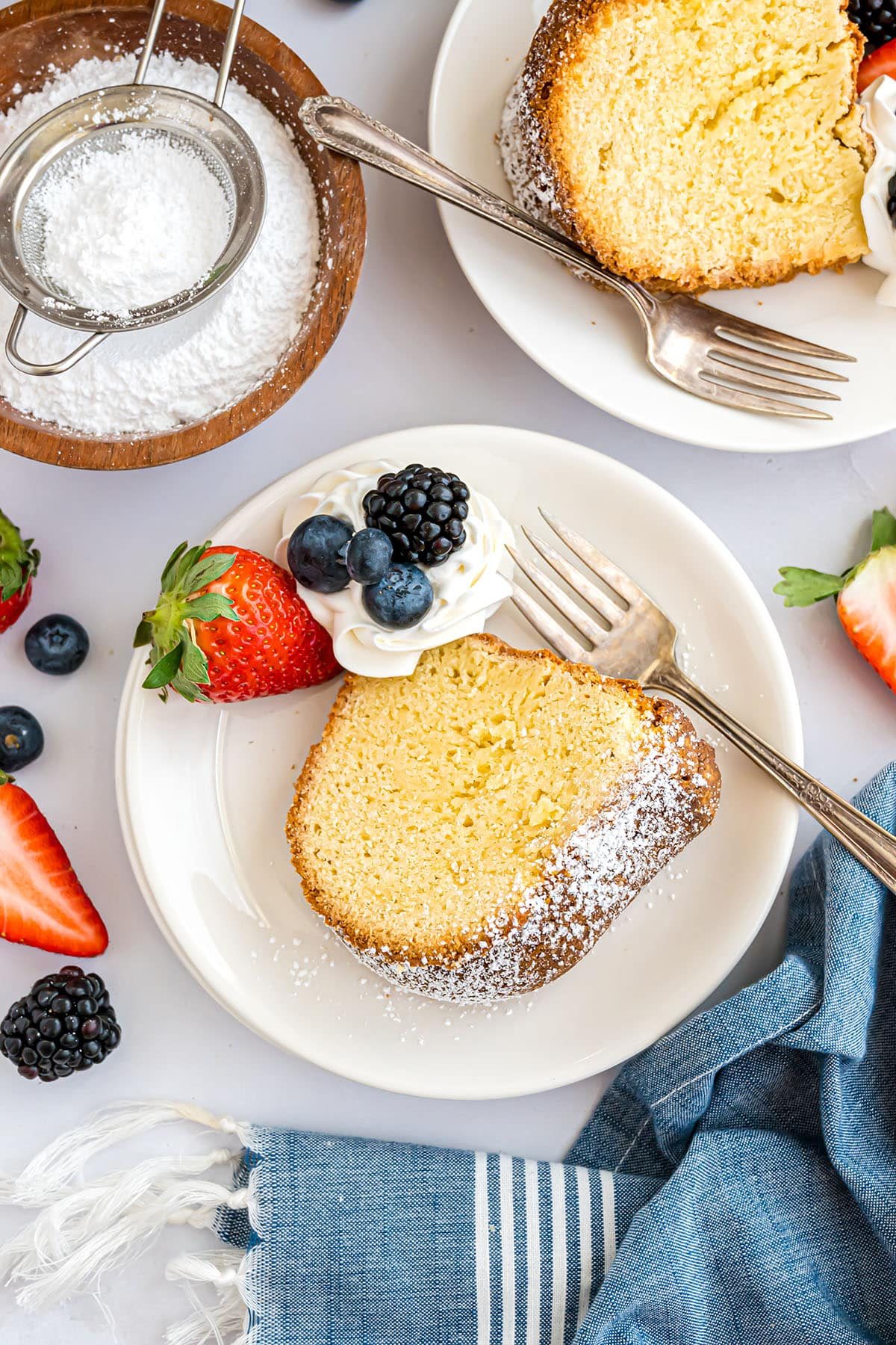 slice of pound cake dusted with powdered sugar with fresh betties