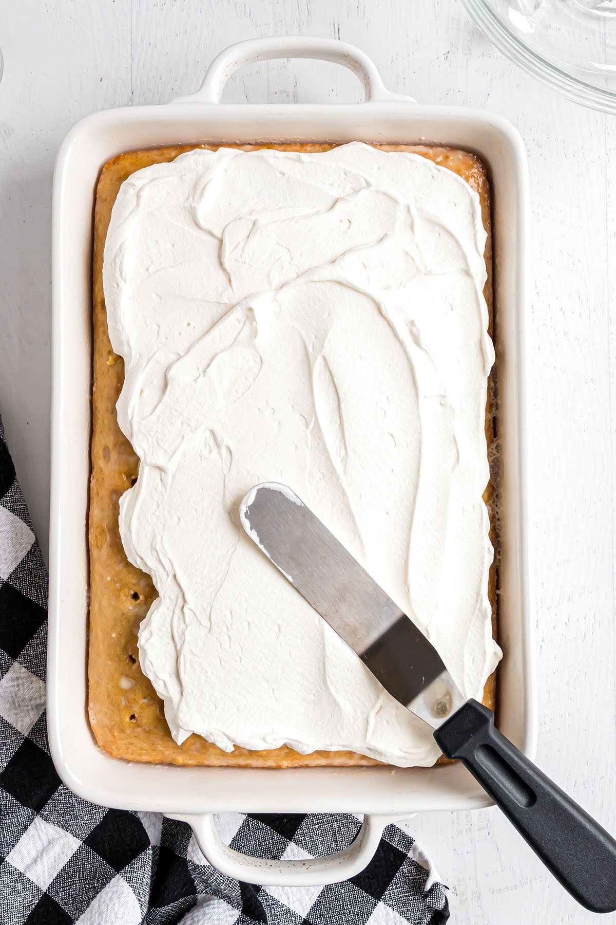 making an easy tres leches cake - Step 4, topping cake with whipped cream