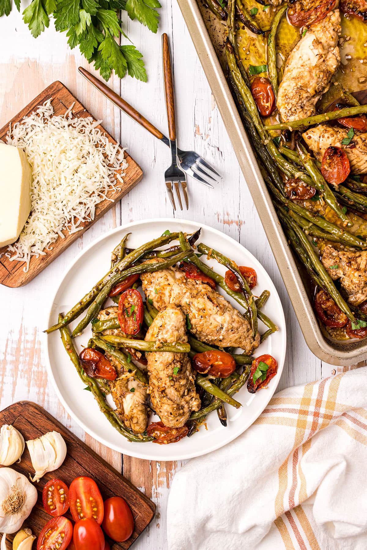sheet pan chicken dinner on a white plate with fresh parmesan cheese on the side