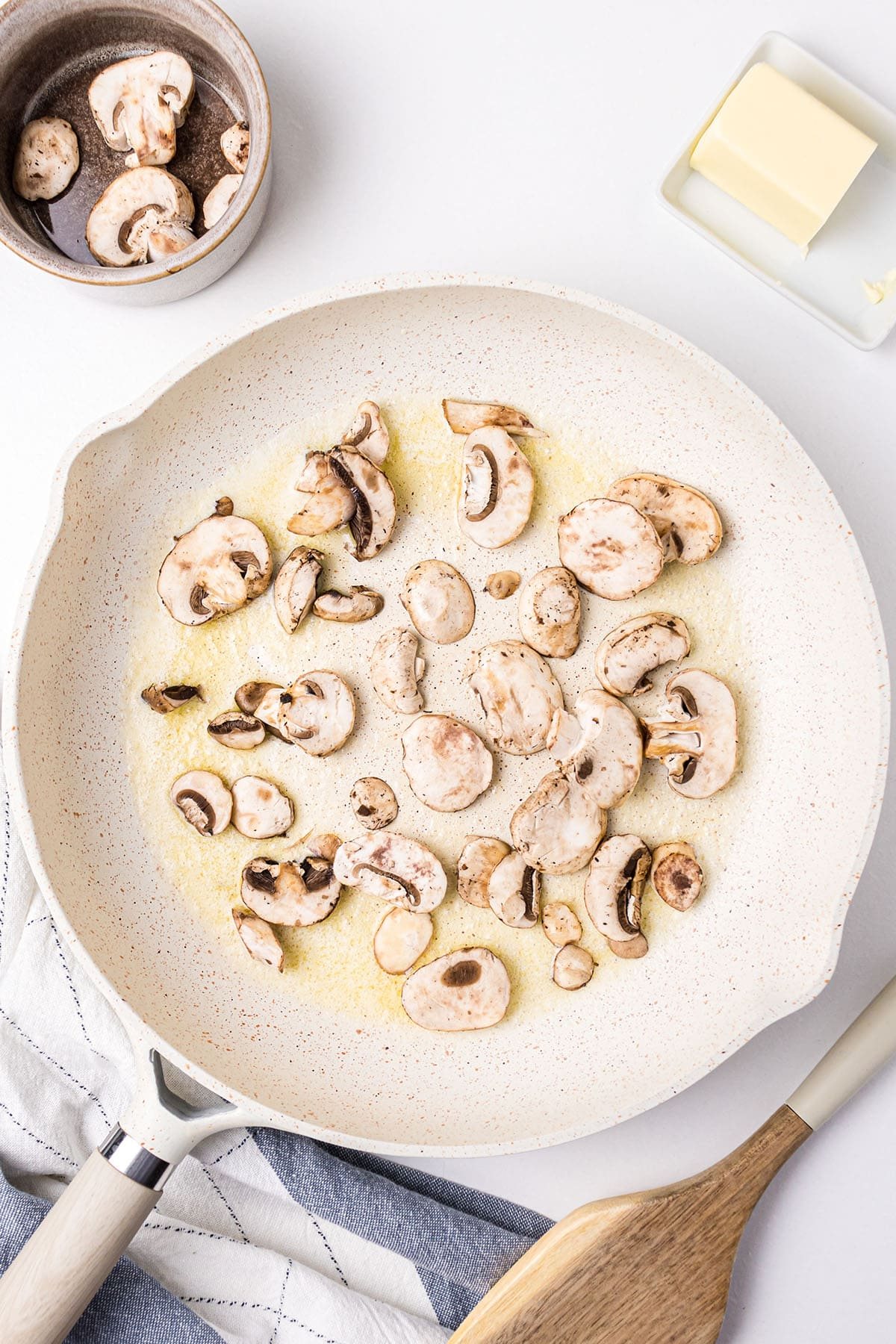 sautéing mushrooms in a white skillet