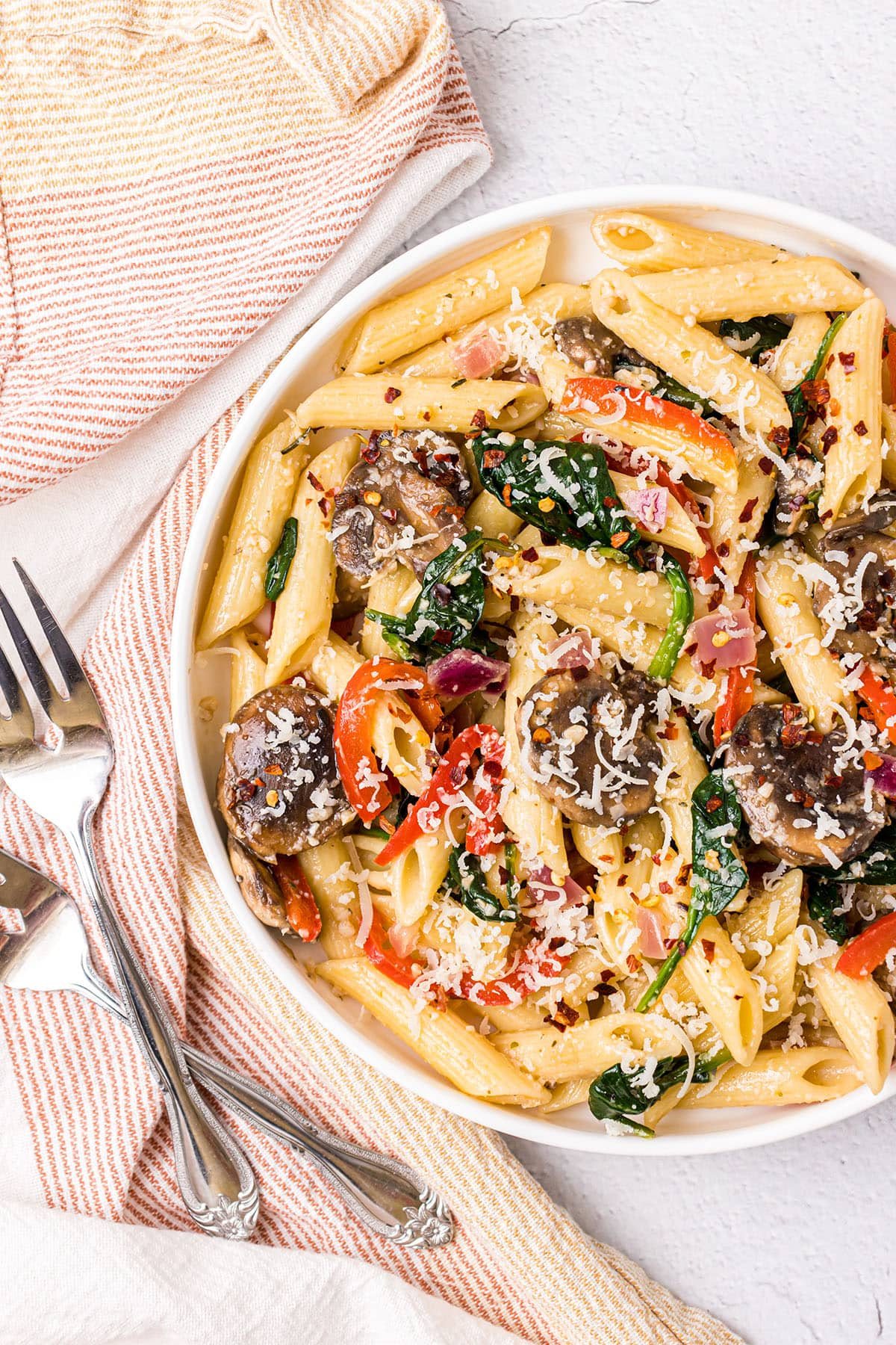 bowl of meatless pasta with fresh veggies on a table with 2 forks