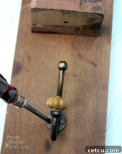 Attaching the coat hook below the shelf on the reclaimed wood sconce
