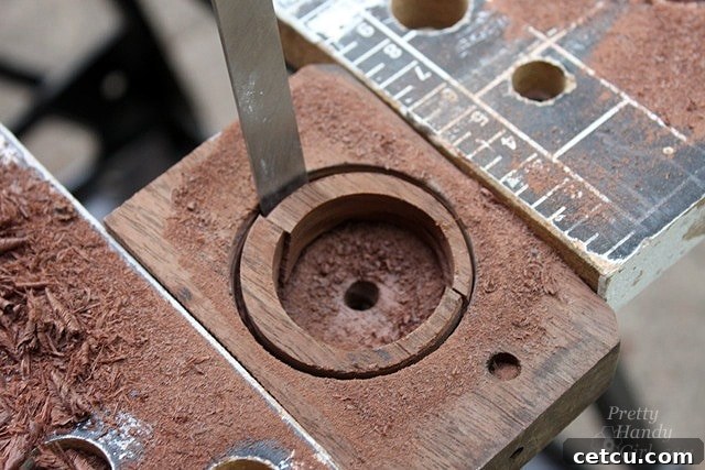 Using a chisel to clean out the drilled hole in the wood shelf