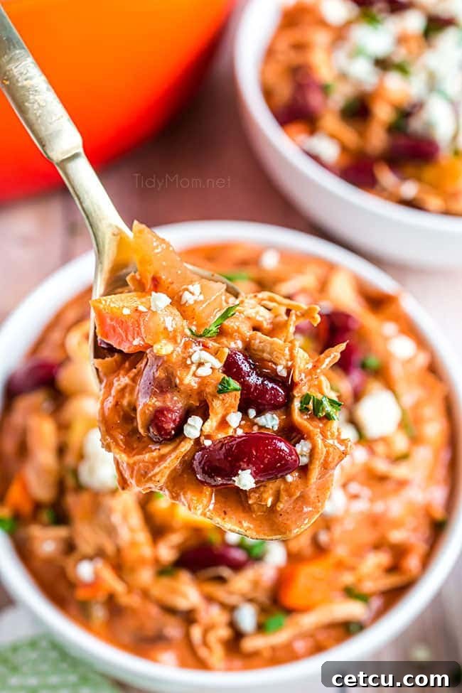 A spoon full of rich Buffalo Chicken Chili, showcasing the creamy texture and chunks of chicken and beans, inviting a taste.