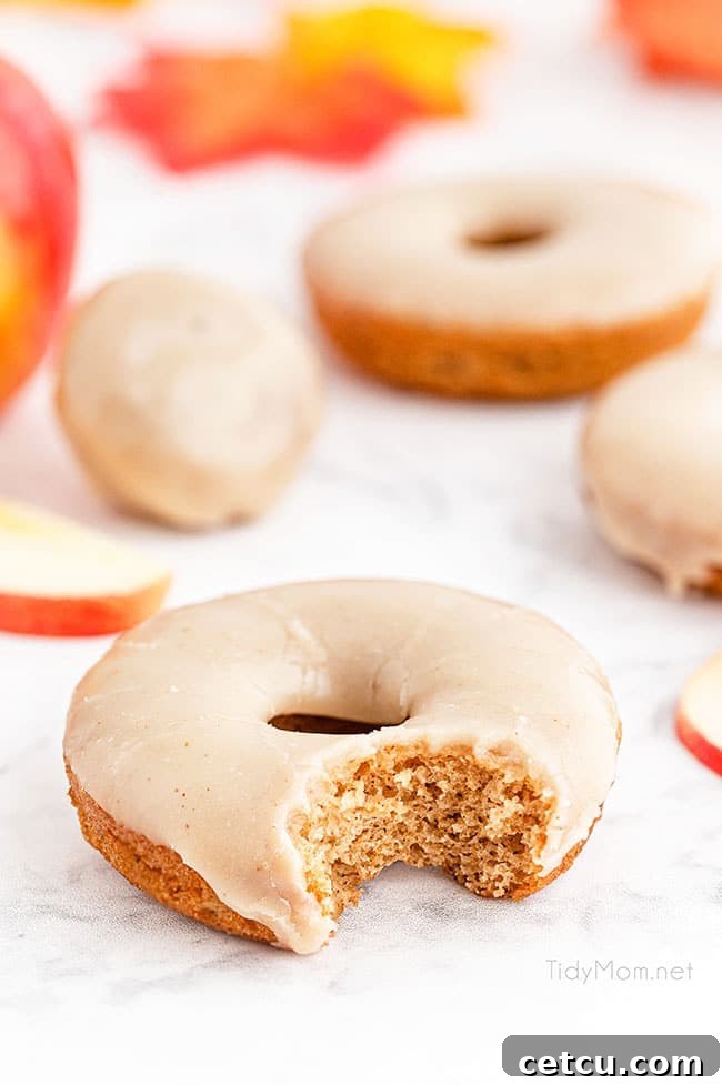 A charming close-up of glazed apple cider donuts and smaller donut holes, artfully arranged on a rustic wooden board, ready for a fall gathering