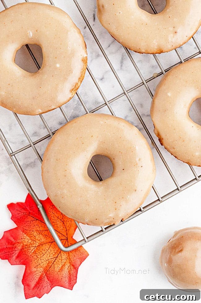 A pristine cooling rack laden with an array of glazed apple cider donuts, glistening with a sweet, nutty topping