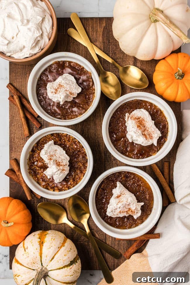 Four individual servings of Pumpkin Crème Brûlée, each topped with a swirl of whipped cream and a dusting of cinnamon, arranged on a rustic wooden surface with autumn decor.