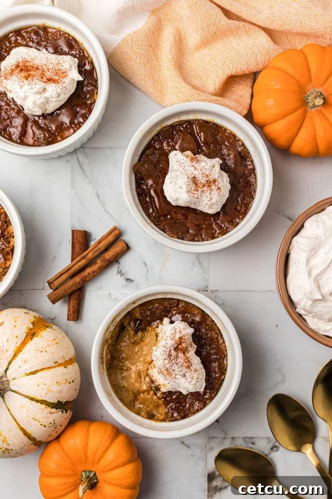 Three individual servings of Pumpkin Crème Brûlée, artfully arranged on a wooden board with small pumpkins and autumn leaves, evoking a cozy holiday atmosphere.