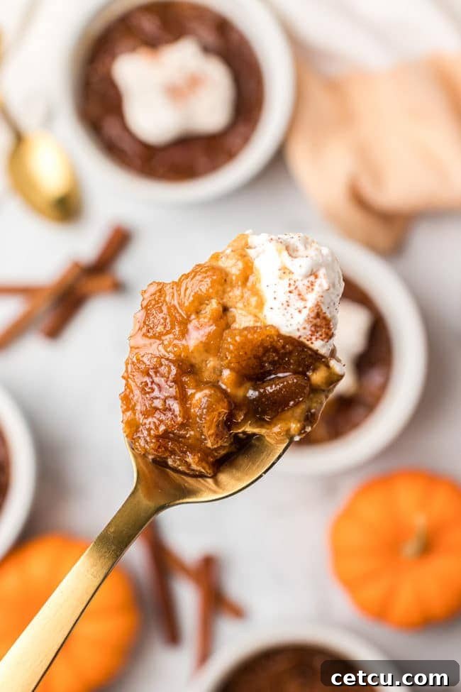 A close-up of a spoonful of Pumpkin Crème Brûlée, showcasing the satisfying crack of the caramelized sugar and the rich, smooth custard.
