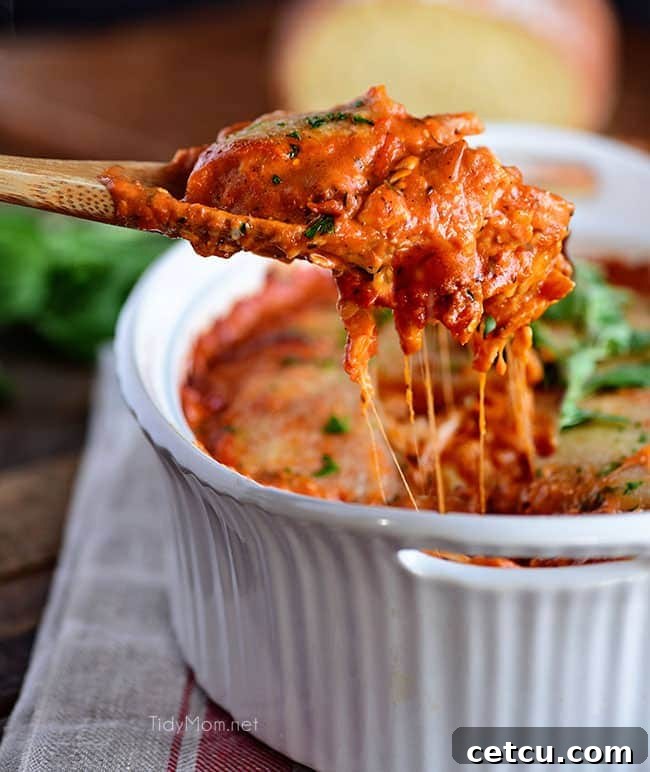 A close-up shot of a cheesy ravioli bake with chicken, showcasing the bubbling melted cheese and rich marinara sauce, making it incredibly appetizing for a family dinner.