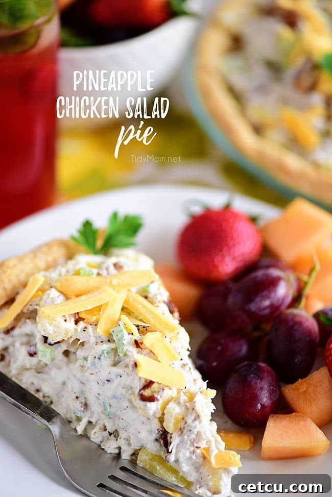 A vibrant slice of Pineapple Chicken Salad Pie on a white plate, garnished with fresh fruit, showcasing its flaky crust and creamy filling. Perfect for brunch or a light meal.