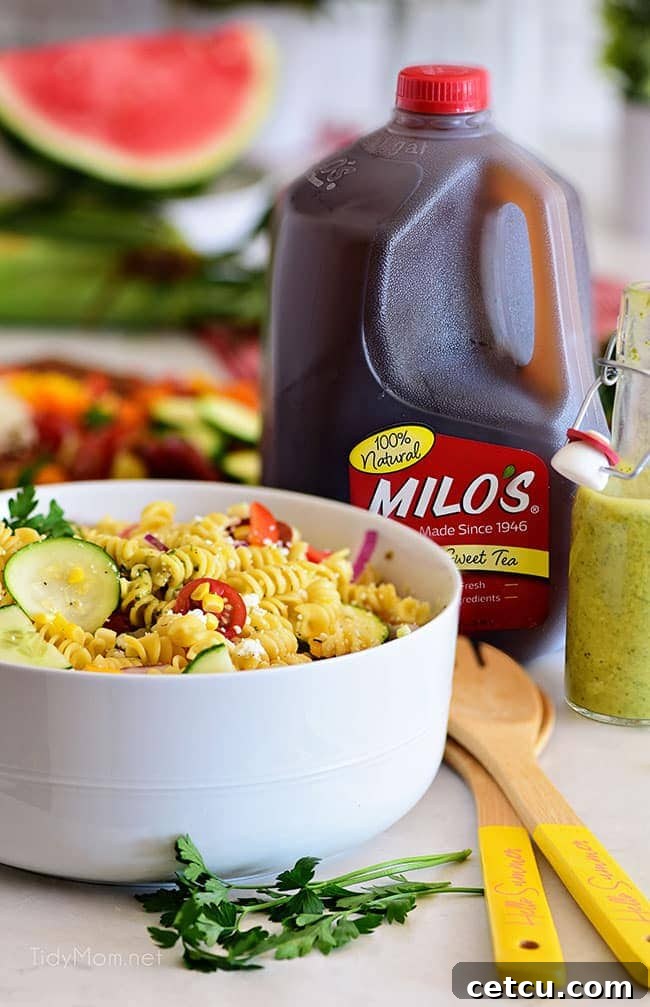 Sunshine Pasta Salad 3 Summer pasta salad in a rustic bowl next to a jug of sweet tea and fresh mint leaves.