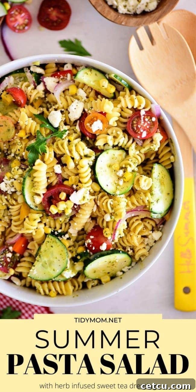 Sunshine Pasta Salad 10 Overhead shot of a vibrant summer pasta salad in a white bowl, garnished with fresh basil leaves.