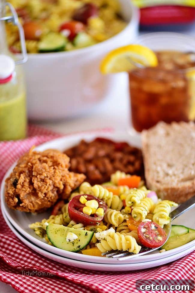 Sunshine Pasta Salad 7 A plate of summer pasta salad served alongside crispy fried chicken, suggesting a hearty meal pairing.