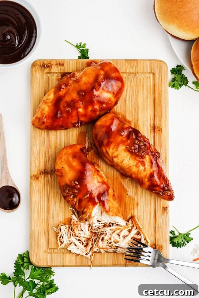 Close-up of shredded BBQ chicken on a wooden cutting board, with visible tender strands of meat