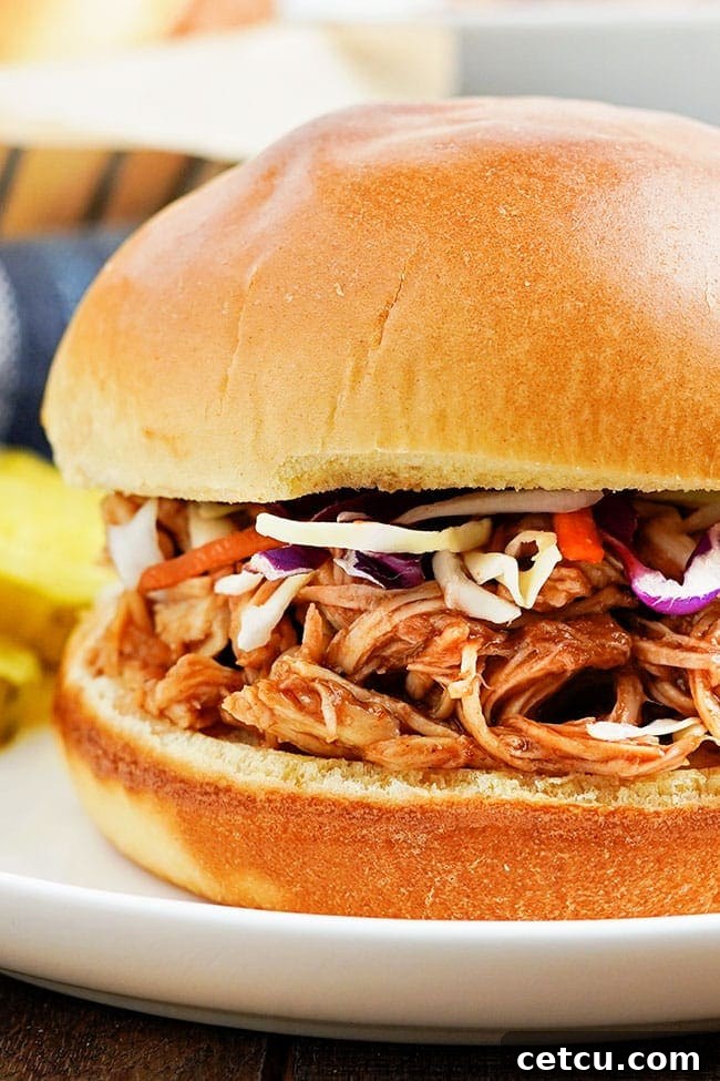 Close-up of a perfectly assembled slow cooker pulled BBQ chicken sandwich on a soft bun