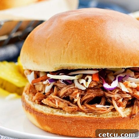 Slow Cooker Pulled BBQ Chicken sandwich on a bun, topped with creamy coleslaw