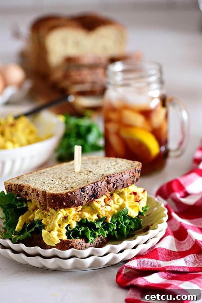 A classic egg salad sandwich with a refreshing glass of iced tea and a red checked napkin.