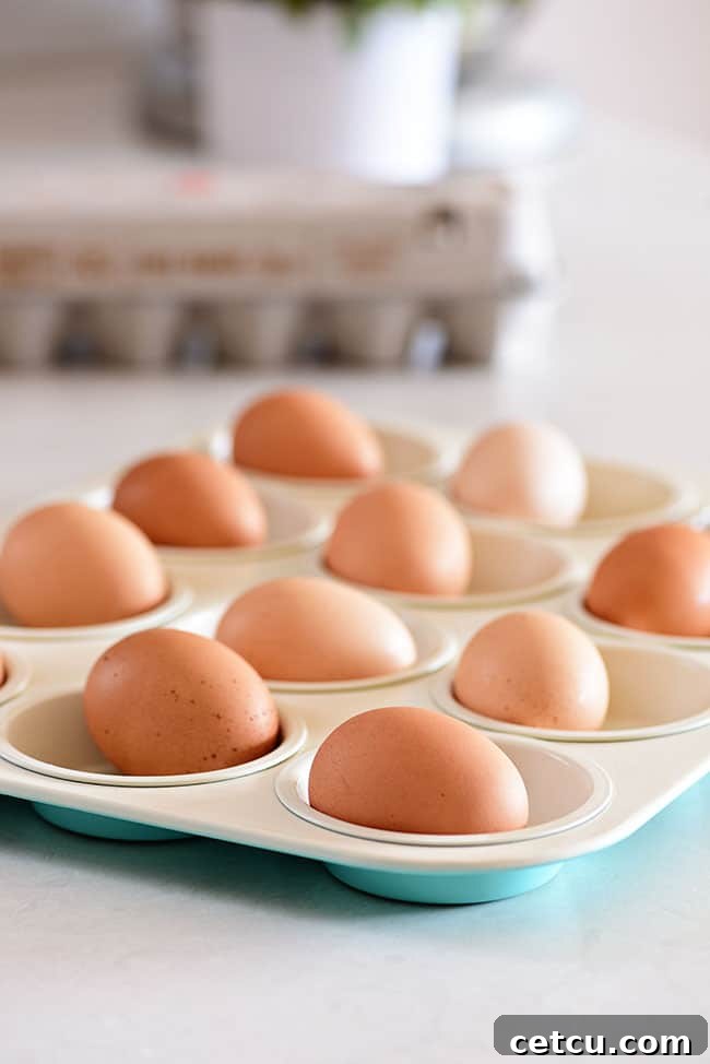 Hard-cooked eggs nestled in a muffin tin, prepared using the oven method.