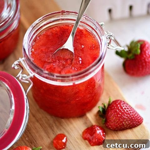 an open jar of no-cook strawberry jam with a spoon