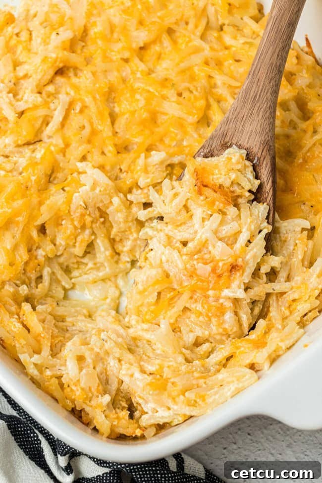 Loaded Cheesy Hashbrown Bake 2 close up of cheesy hashbrown casserole in a baking dish with a wooden spoon