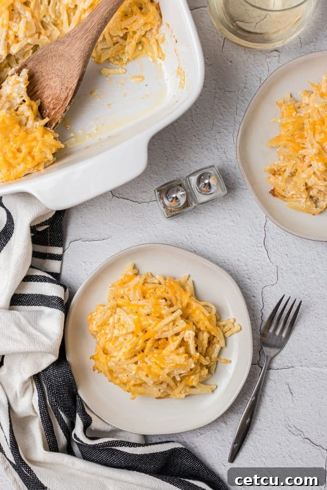 Loaded Cheesy Hashbrown Bake 7 Cheesy hashbrown casserole in a white baking dish served up on two plates