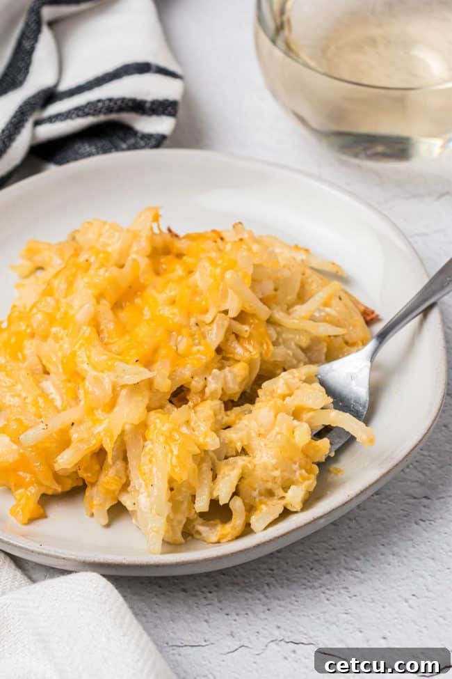 Loaded Cheesy Hashbrown Bake 10 plate of cheesy potato casserole with a fork