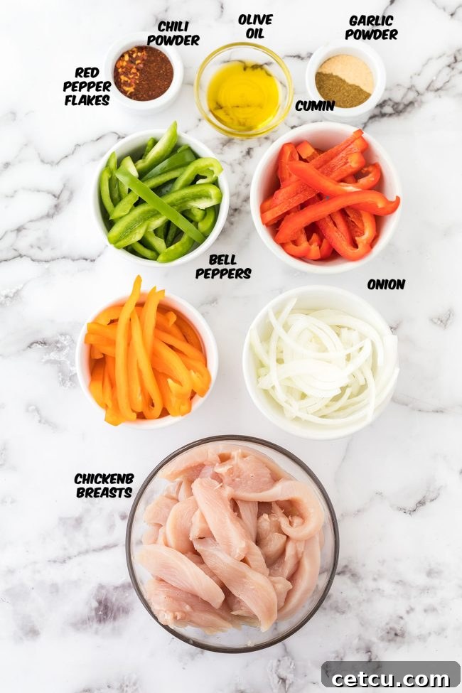 Fresh ingredients for sheet pan chicken fajitas, including sliced chicken breast, colorful bell peppers, and white onion, ready to be seasoned.